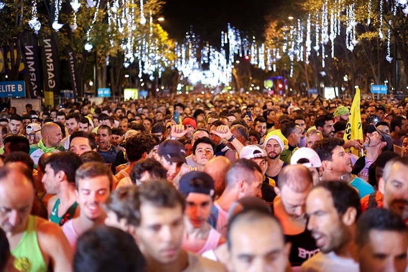 multidão a correr em rua enfeitada de Natal